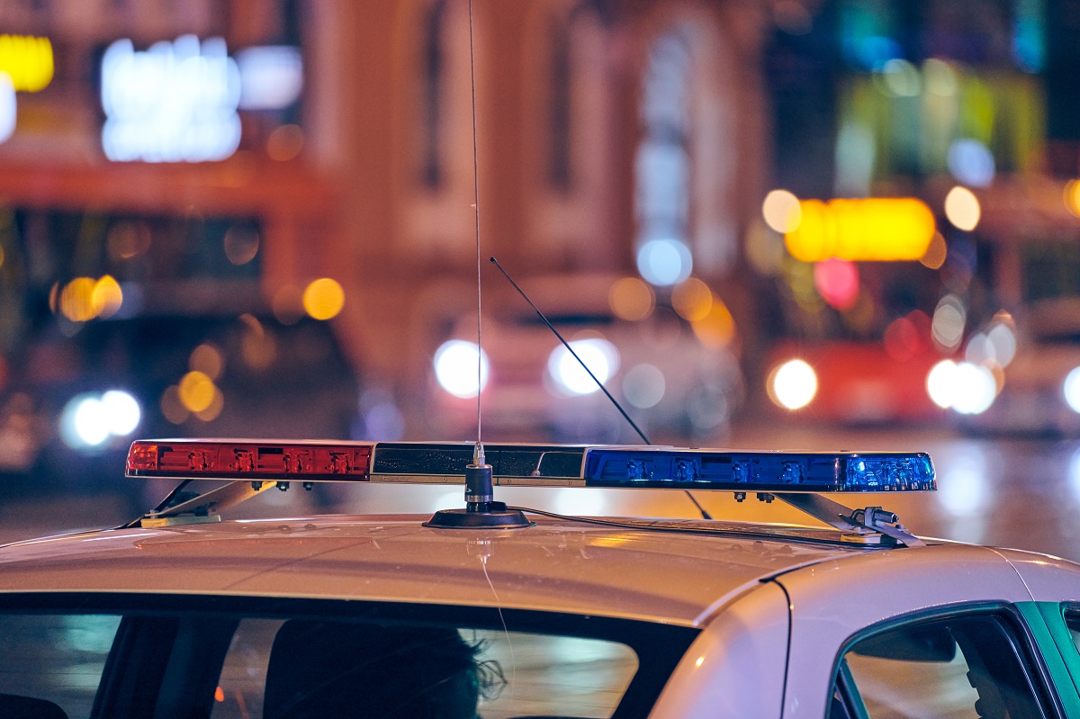 The roof and lights of a police car against a city street at night.