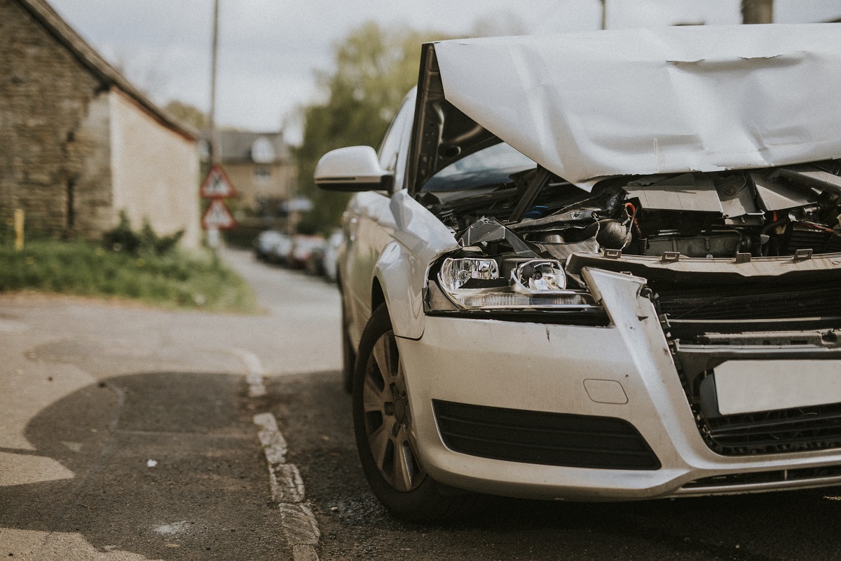 A white car's hood is folded in half from damage.