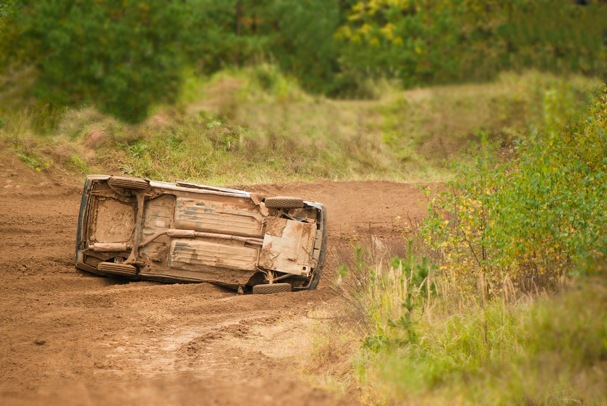 A car sits on its side in a patch of dirt after a rollover accident.