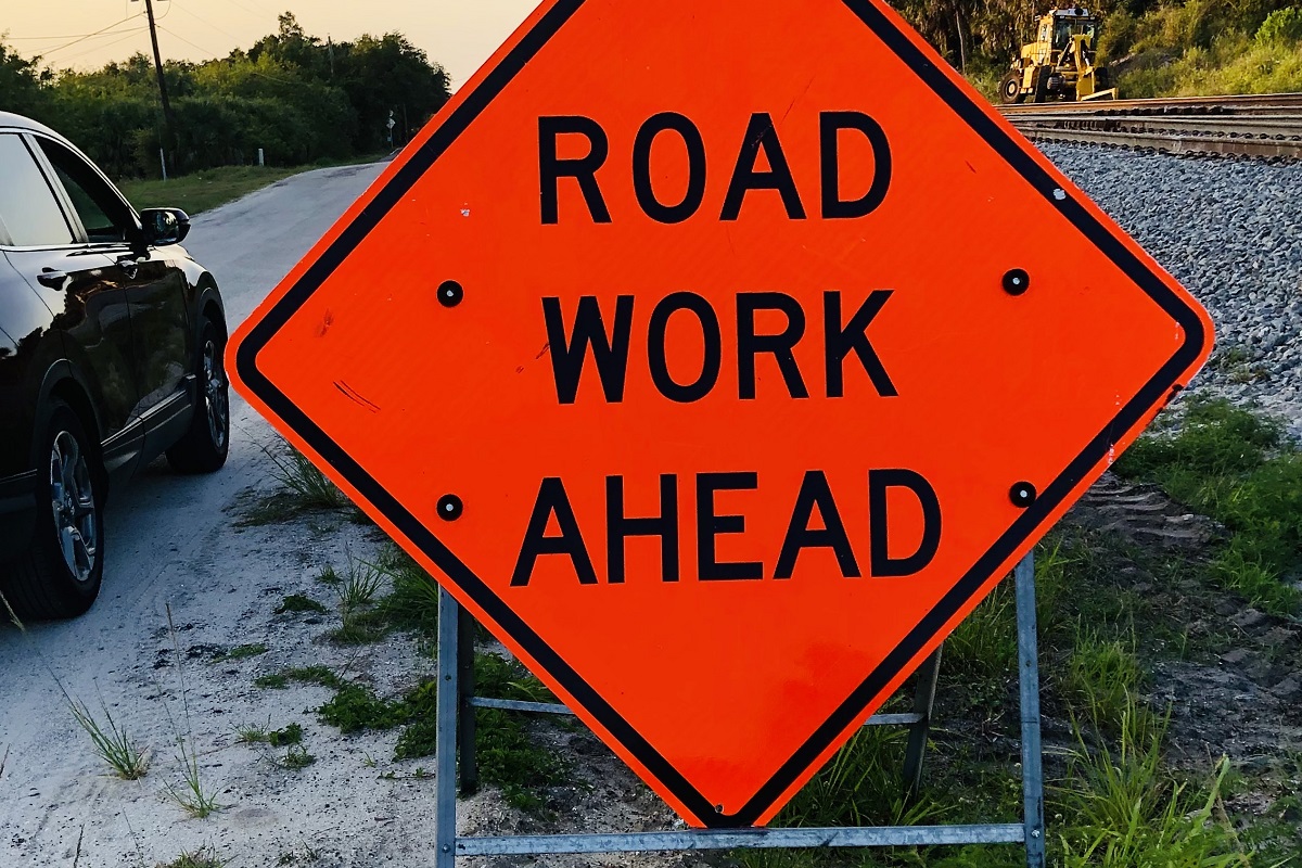 A red road work ahead sign on the side of the road.