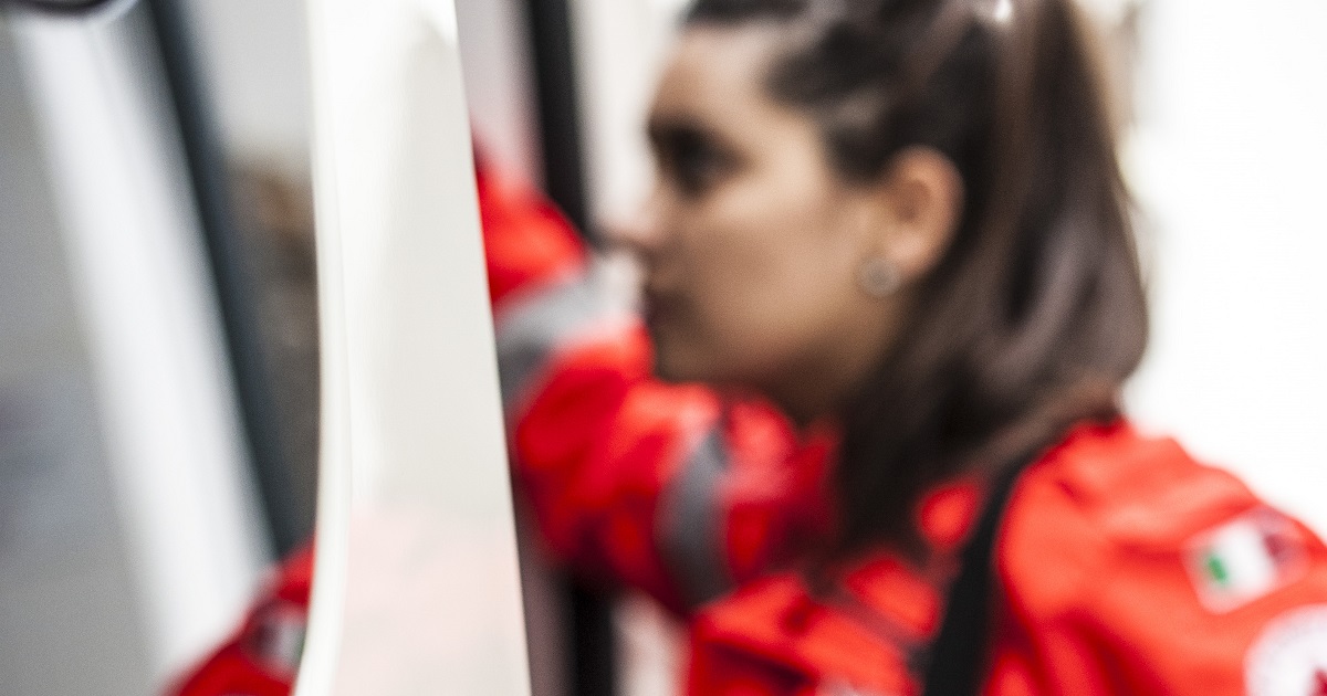 A paramedic in red climbs into an ambulance.