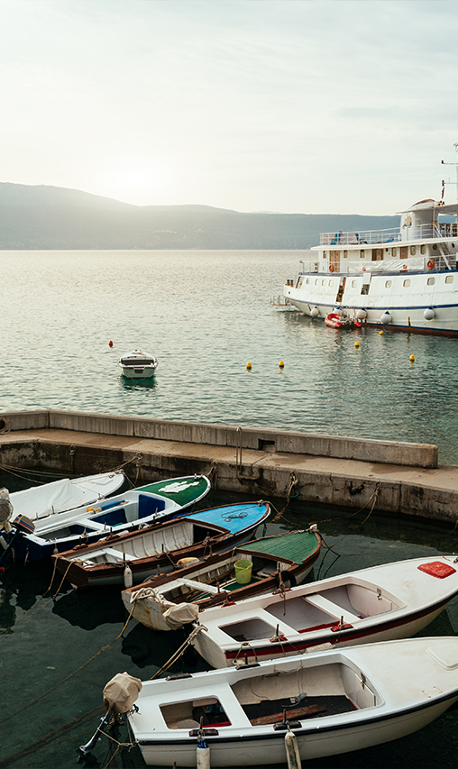 A curved dock on a body of water with seven small motorboats and a larger boat at another dock.
