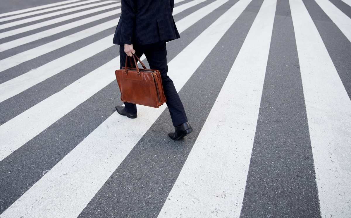 A businessman walking on a crosswalk.