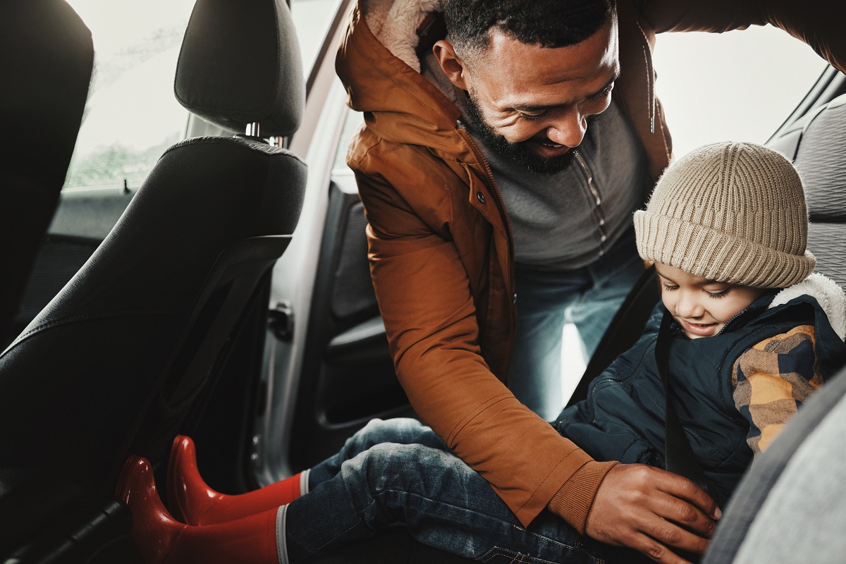 A father buckling his child into a car seat