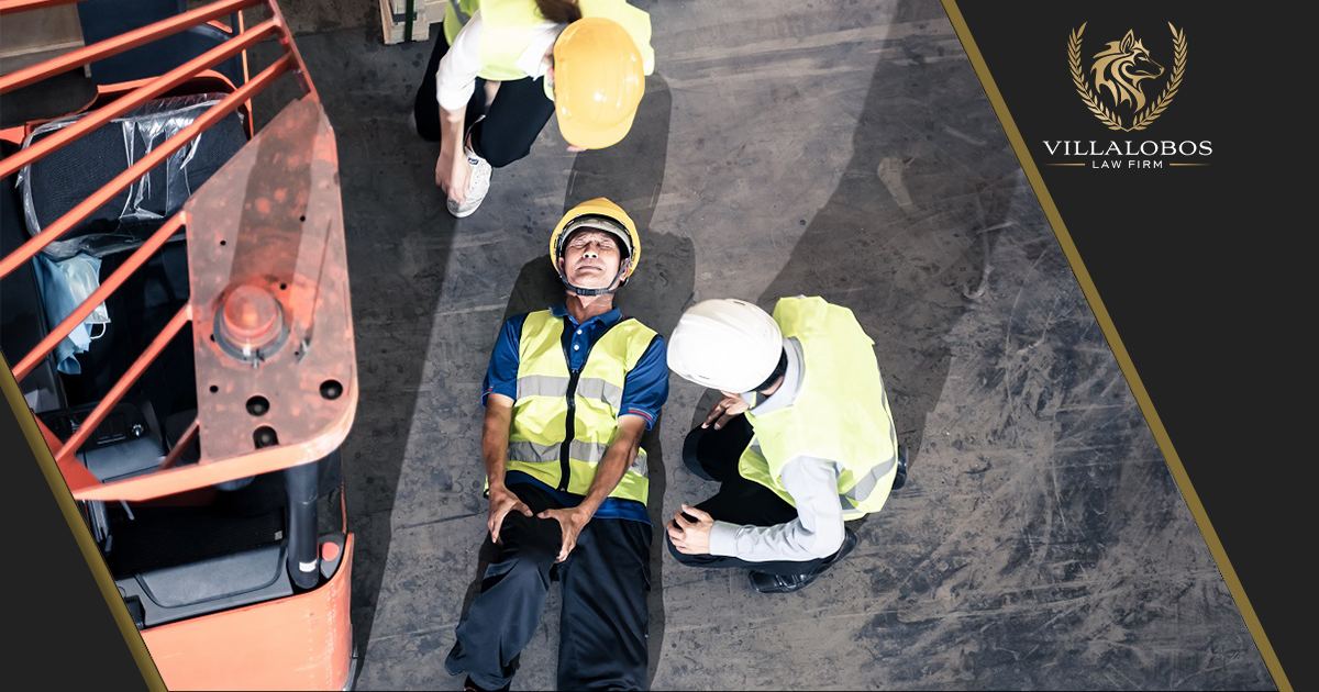 Two workers standing over a worker lying on the ground holding his leg in pain after a workplace injury