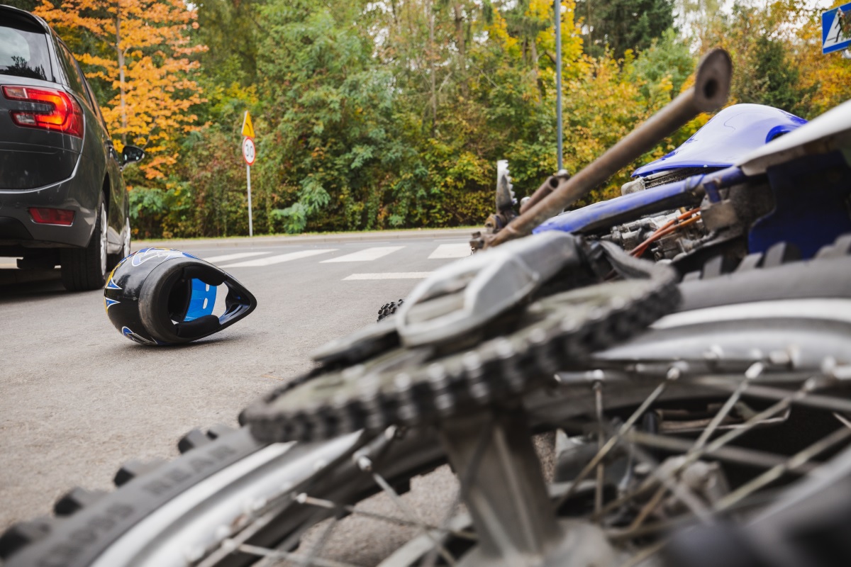 A motorcycle and helmet lying on the ground after a car accident