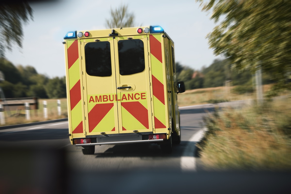 An ambulance driving on the road with lights engaged