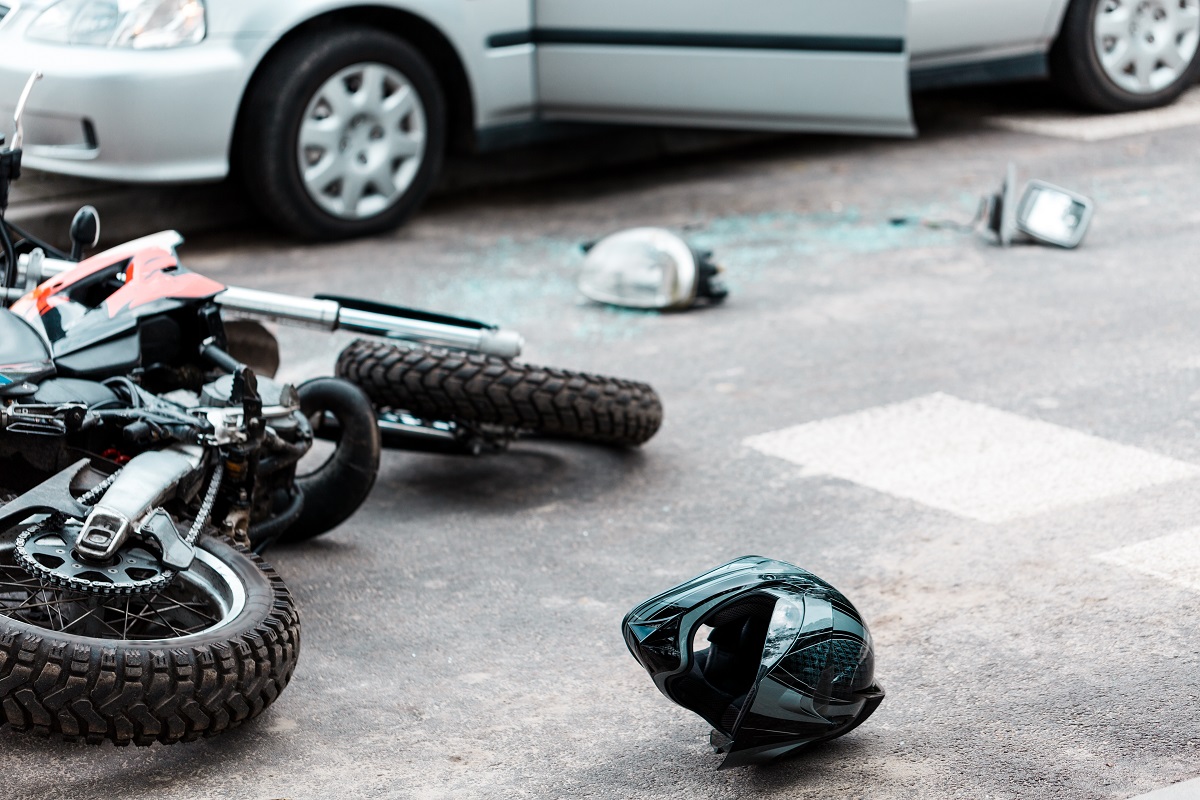 A motorcycle and helmet lying on the road after a crash